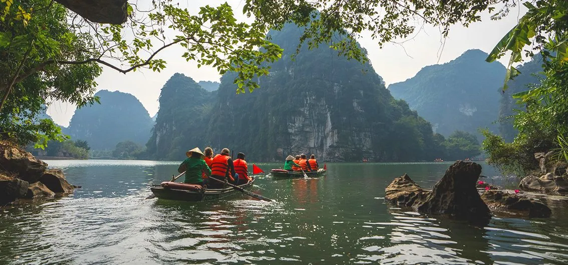 Ruderboote zwischen Karstfelsen in der Halong-Bucht