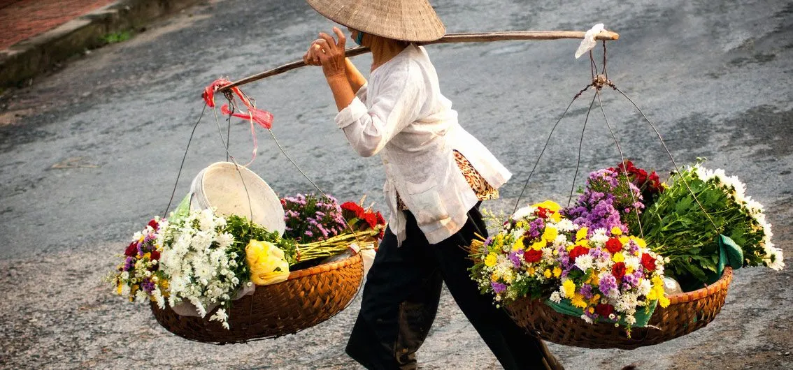 Blumenverkäuferin mit Tragestange in Hanoi