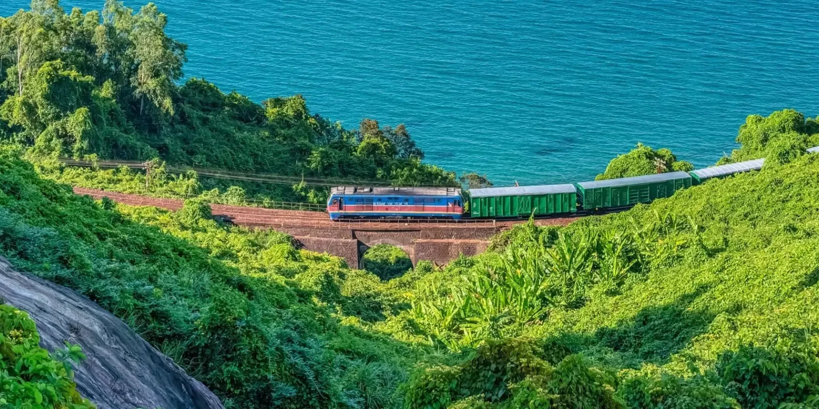 Zug auf der Küstenstrecke Zentralvietnams zwischen dichtem Grün und dem Meer