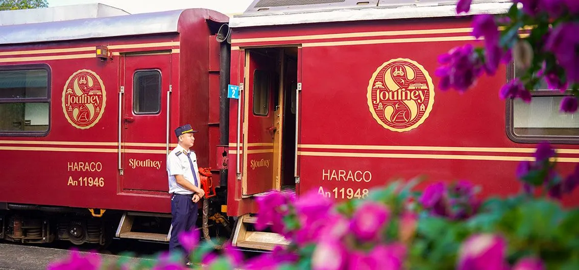 Der rote SJourney am Bahnsteig, davor blühende Bougainvillea